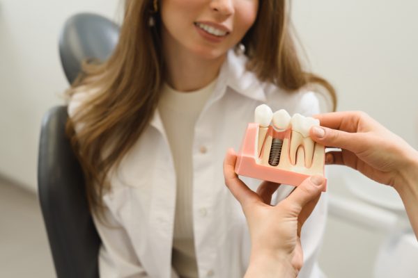 dentist showing a patient a model of dental implant