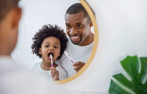 a father checking if his son is brushing his teeth correctly