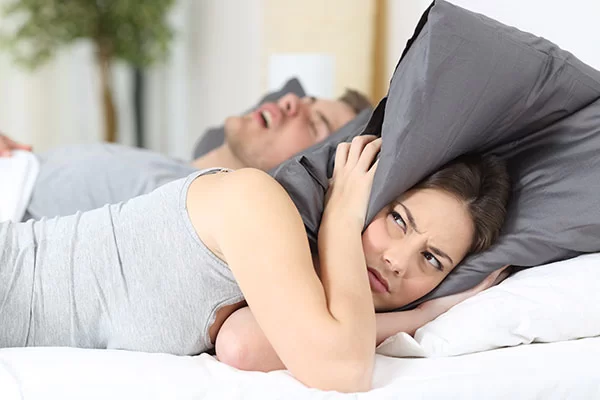 woman annoyed by her bed partner's snoring