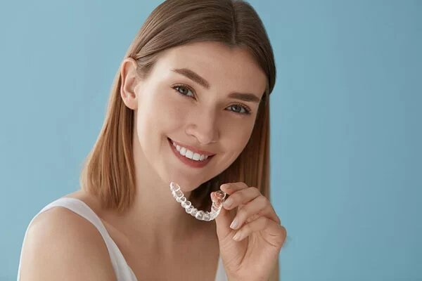 young lady holding a clear aligner tray