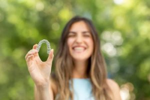 young girl holding an Invisalign clear aligner