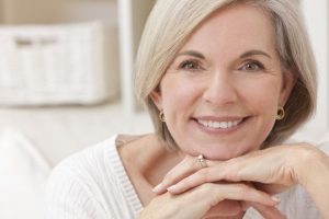 Middle-aged woman smiling after receiving full mouth reconstruction