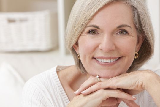 Middle-aged woman smiling after receiving full mouth reconstruction