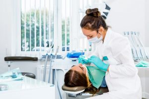 dentist performing teeth cleaning to a patient