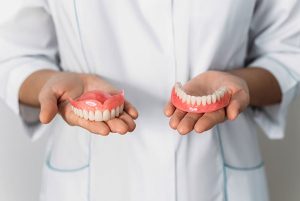 Dentist holding full mouth reconstruction dentures in both hands, showcasing dental restoration options for patients at Brown and Baran Family Dentistry.